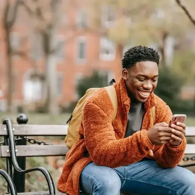 Adulto joven de sector popular usando el celular con confianza